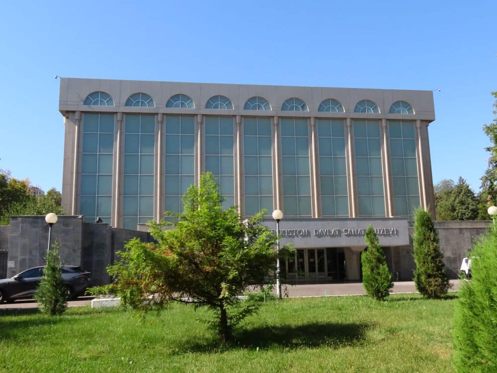 A large rectangular building with vertical half-columns up its face and small semi-circular windows along the roof.
